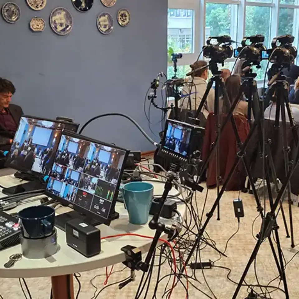 a group of people sitting around a table with multiple cameras