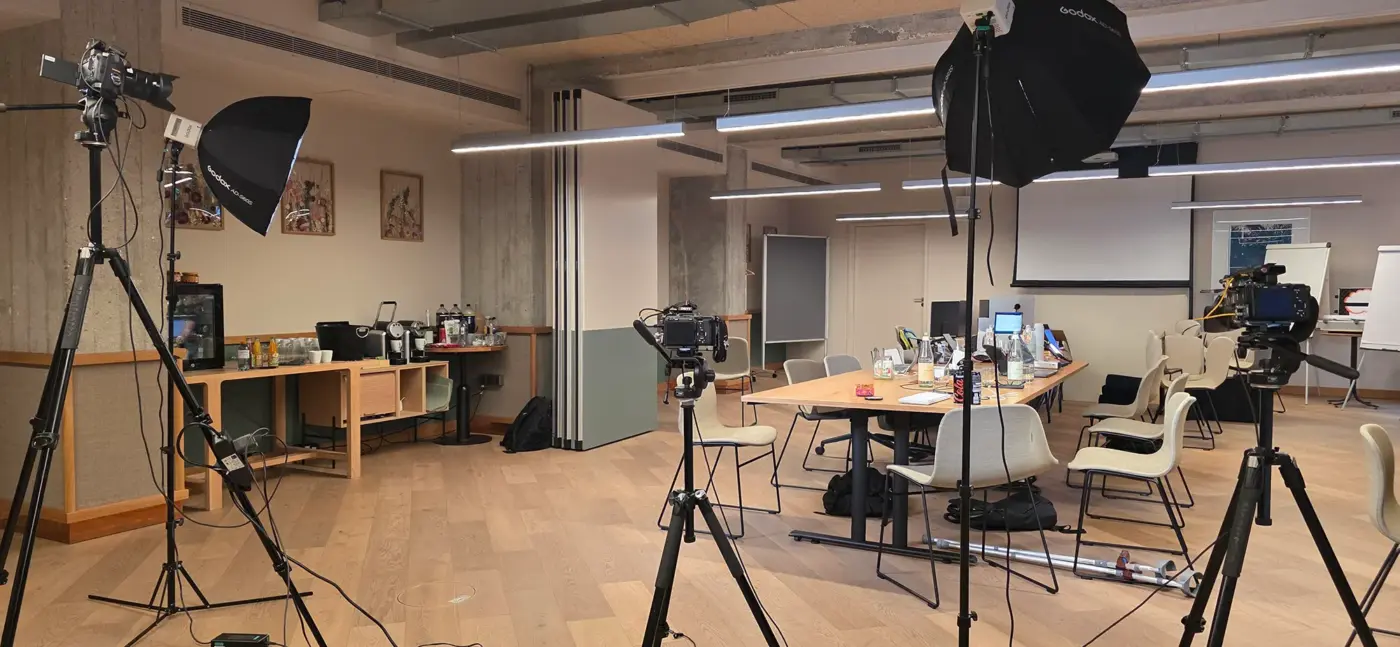 Video Podcast 2 Professionelles Indoor-Filmset von 3DMS Filmproduktion in einem Konferenzraum der WunderLocke München mit drei Kameras, Godox-Softboxen und einem großen Besprechungstisch.