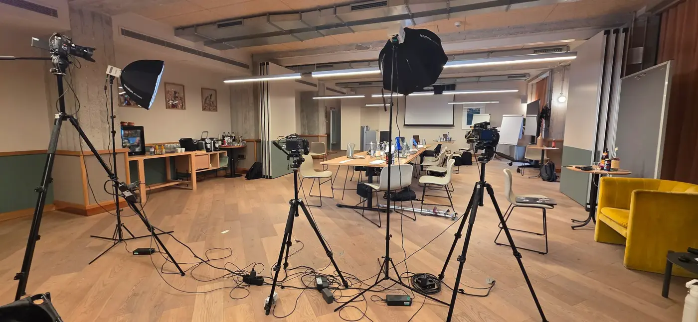 Video Podcast 12 Weitwinkelaufnahme eines professionellen Video-Podcast-Sets im Innenraum der WunderLocke München mit drei Kameras, Godox-Blitzköpfen und Softboxen sowie einem modernen Besprechungstisch.