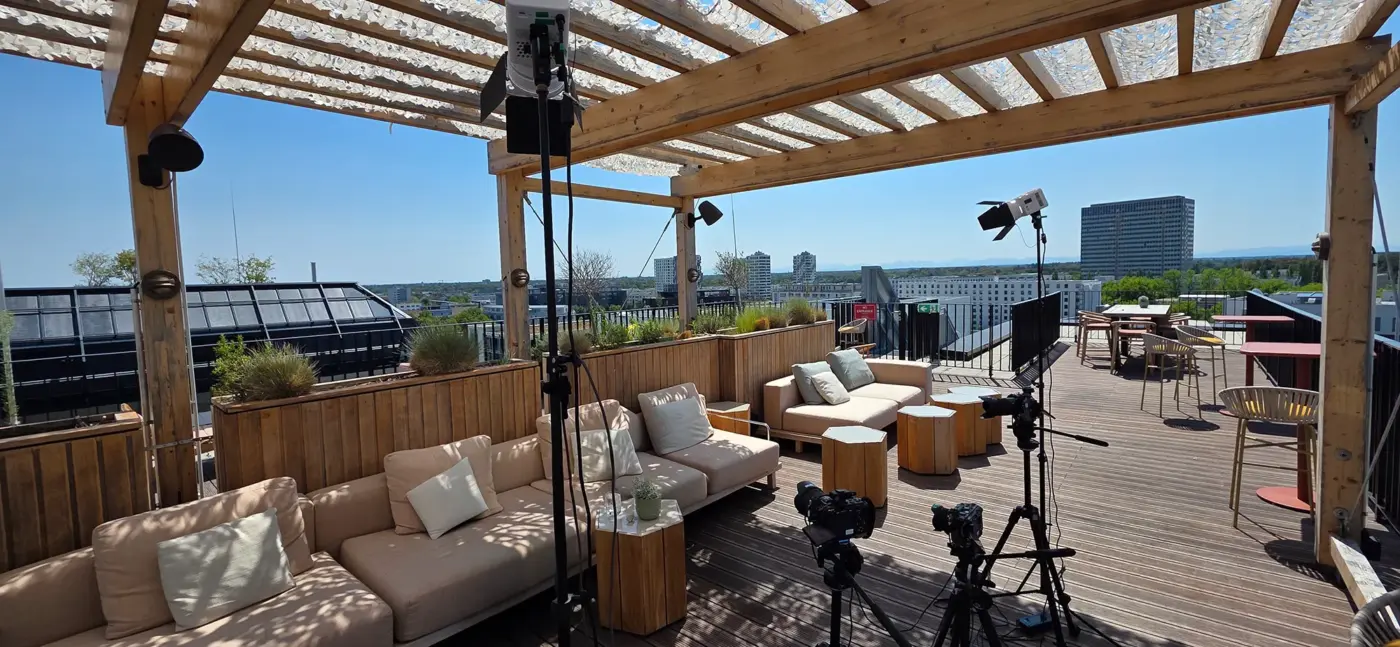 Interview 12 Panoramic view of a professional film set on the WunderLocke rooftop terrace in Munich featuring cameras, Godox lighting, and a wide view over the city skyline.