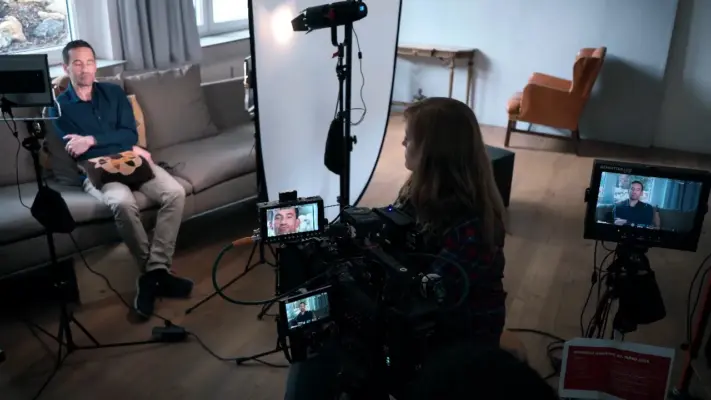 Werbespot 11 Making-of eines Werbespot- und Interview-Drehs in München mit Kameratechnik, Monitoren, professioneller Beleuchtung und einem Interviewpartner auf einem Sofa.