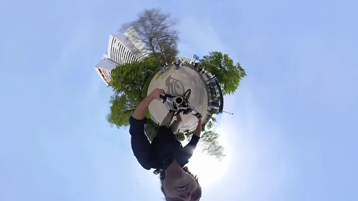 360 video 2 Little-planet view of a 360-degree camera move with a tower block, trees and blue sky.
