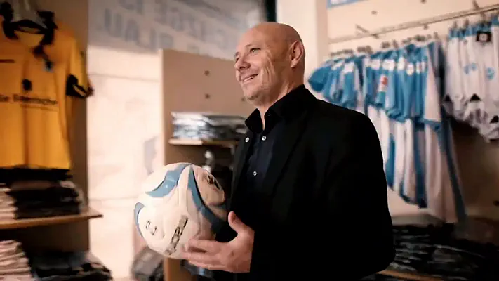 Bewerbungsvideo 4 Mann mit Fußball in der Hand im Fanshop zwischen Trikots und Merchandise.