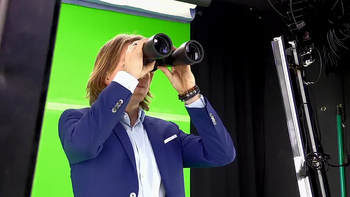 Filmstudio mieten 5 Darsteller im Anzug blickt durch ein Fernglas vor dem Green Screen.