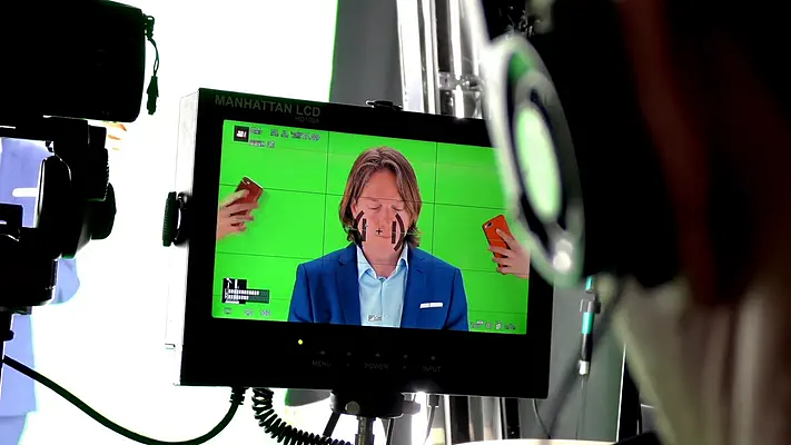 Filmstudio mieten 2 Kontrollmonitor zeigt einen Darsteller im Anzug vor dem Green Screen.