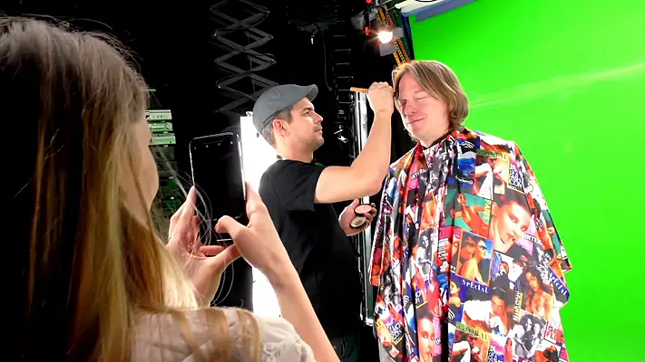 Filmstudio mieten 1 Maskenbildner schminkt einen Darsteller vor dem Green Screen, eine Mitarbeiterin fotografiert.