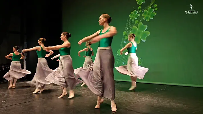 Making Of Video 2 Group of dancers in flowing skirts performing a choreography on stage.